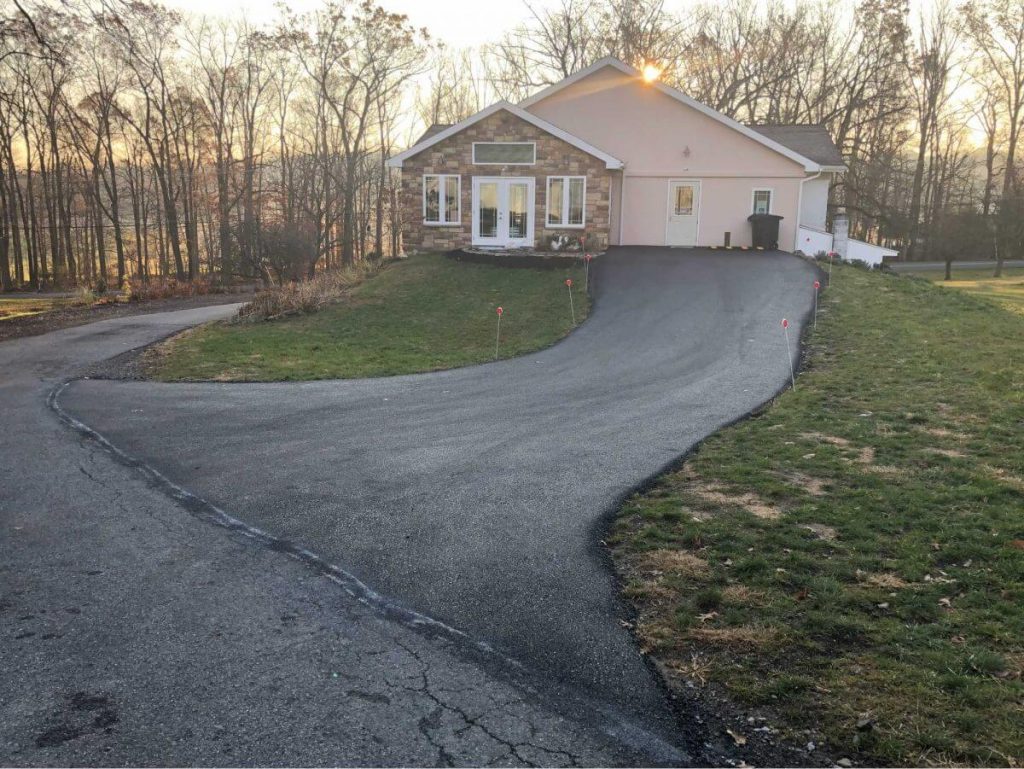 newly paved driveway up a hill to the back of a house, paving services
